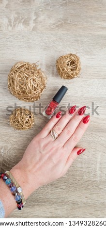 Female hand with long nails and a bottle with red nail polish