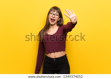 Woman with glasses over yellow wall happy and counting four with fingers