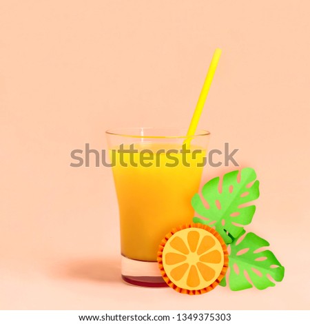 Fresh orange juice in glass for tropical party. Decorating summer drinks. Paper decorations: circle of orange and monstera leaves. Paper art and paper craft. Minimal style 