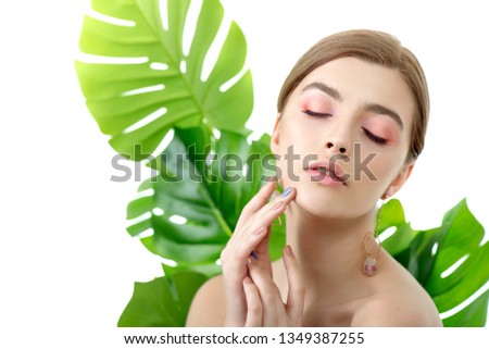 Beautiful young woman with perfect skin and natural make up posing front of plant tropical green leaves background. Teen model are of her face and body. SPA, wellness, bodycare and skincare.