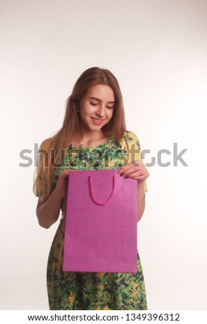 Portrait of young blonde lady isolated white background posing with glitter shoping bag looking aside happy smiling cheerful