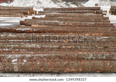 Piles or stacks of wooden logs or trunks in the snow in winter ready for construction, building, heating or enery in a fjord in Nordland, Norway.