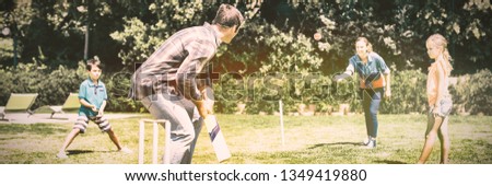 Happy family playing cricket in park on a sunny day
