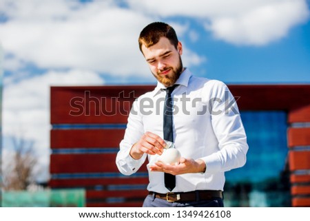 Businessman in white shirt with piggy box and money at city outdoor.