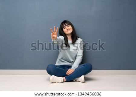 Woman sitting on the floor happy and counting three with fingers