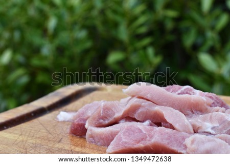 Raw pork strips on wooden cutting board