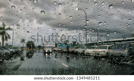 Water droplets with abstract blur background as viewed from car window on a rainy day. Selective focus.
