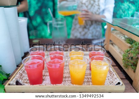 Orange juice squeezed with red juice that is inserted into the glass and placed in a wooden tray