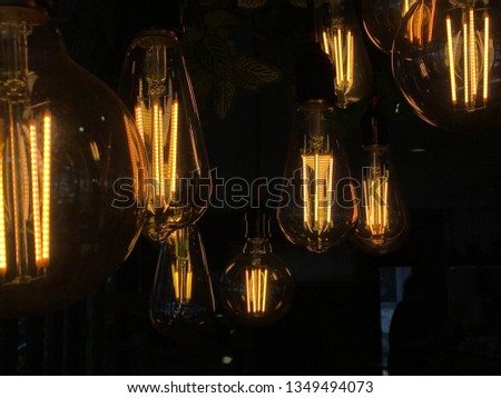 A quintet of vintage hanging light bulbs over a dark background