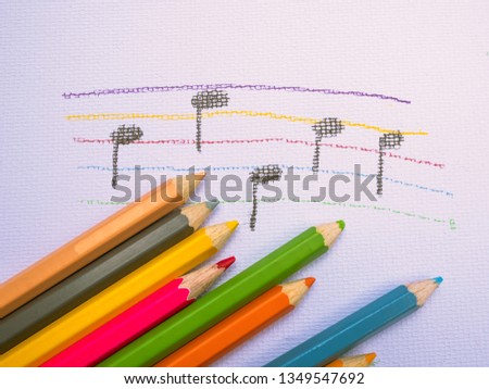 Color pencils place on white paper background with Music note drawing. Education concept.