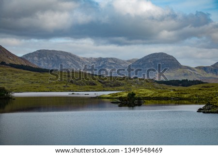 The valleys, countryside and mountains of Connemara, County Galway in Ireland. Beyond the lakes and rolling hills, the large mountains stand under a cloudy sky.