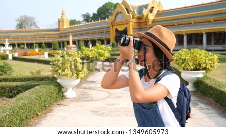 Beautiful young Asia girl tourist taking picture at Chaimongkol Pagoda famous landmark at Roiet Thailand.