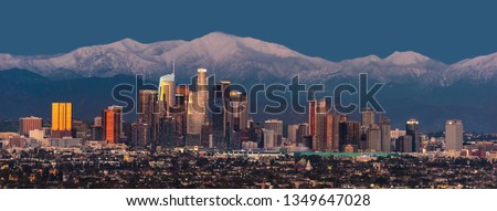 Downtown Los Angeles skyline with snow capped mountains behind at twilight