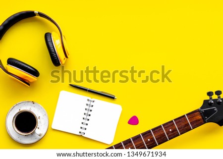 Professional dj instruments with headphones, guitar, notebook and coffee on yellow background top view mockup