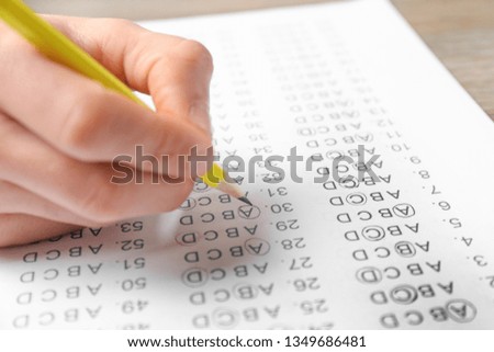 Student filling answer sheet at table, closeup