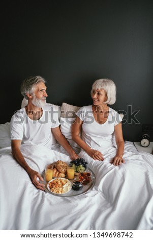 Good morning! Senior family couple enjoying breakfast in bed.