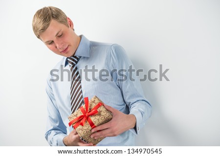 Smiling businessman holding gift box with red ribbon
