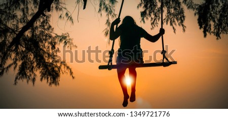 Silhouette of a girl swinging on a swing against the sunset sky. Thailand, Koh Chang island