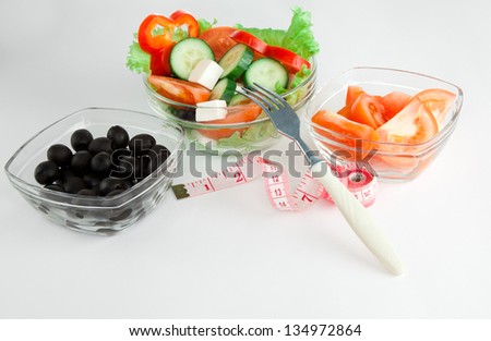 Picture of a plates with greek salad, tomatoes  and black olives on table