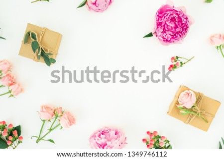 Floral frame of pink peonies, roses, hypericum and eucalyptus with clipboard and gifts on white background. Flat lay, top view