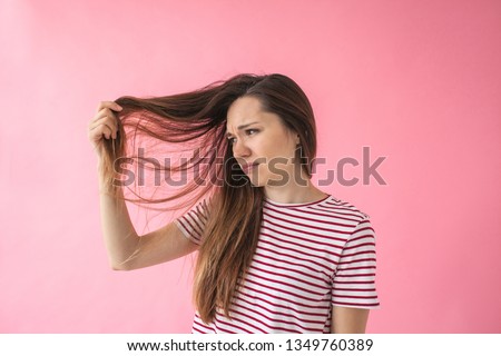 The girl is not happy with her hair and shows split ends or dandruff or dry hair or other problems. Royalty-Free Stock Photo #1349760389