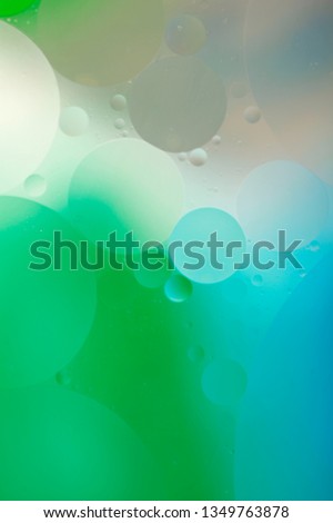 Gentle abstract blurred background. The texture of the liquid with circles and bubbles of green, blue and gray colors of different sizes. Cropped shot, macro, vertical, nobody, free space for text.