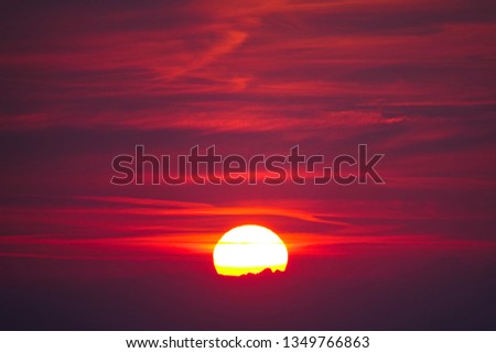 Picturesque view of the colorful sky and golden sun on a tranquil summer morning in untouched nature. Glowing sphere illuminates the sky at sunrise. Dramatic sun and beautiful purple hued summer sky.
