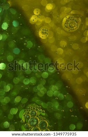 Abstract blurred background. The texture of the liquid with circles and bubbles of green and yellow with a border on the diagonal. Cropped shot, macro, vertical, nobody, free space for text.