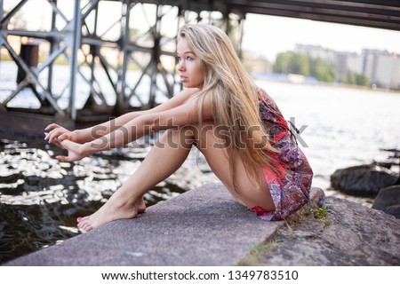 Beautiful blond girl posing for photo in dress at the park