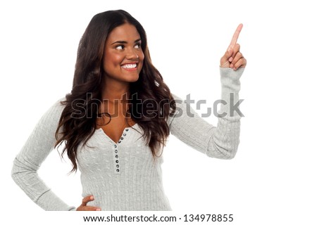 Charming smiling african woman pointing upwards, white background.