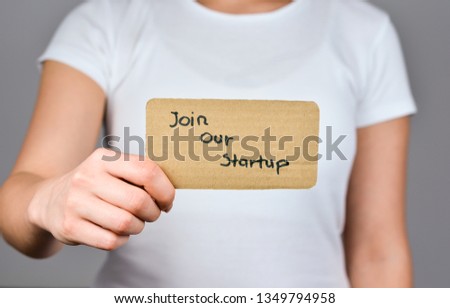  Join our Startup phrase handwritten  on square  cardboard paper holding by young women  in hand.