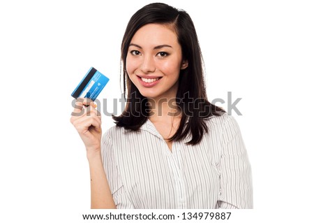 Smiling asian young female model holding up credit card.