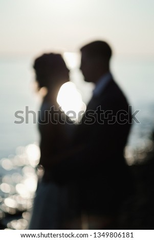 Loving couple at sunset. Blurred picture with glowing water background. Wedding and dating concept.