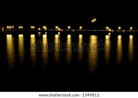 dock at nighttime with reflecting lights in the water