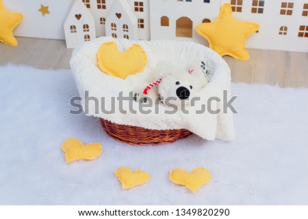 White wooden decorative houses on blue wall background. Toy houses in Christmas decor. The interior of the children's room. Paper garland in the form of stars. Soft toy white bear in a wicker basket.