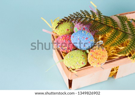 Easter eggs in egg cartoon box on blue background close up. Festive decorations. Happy Easter