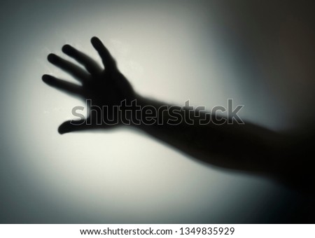 Silhouette of five fingers on a man's hand with a bright light spot. Dramatic film grain
