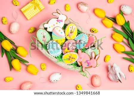Easter homemade gingerbread cookies  in a basket on a pink background with tulips and easter decorations. Gingerbread in shape of easter bunny and easter eggs.