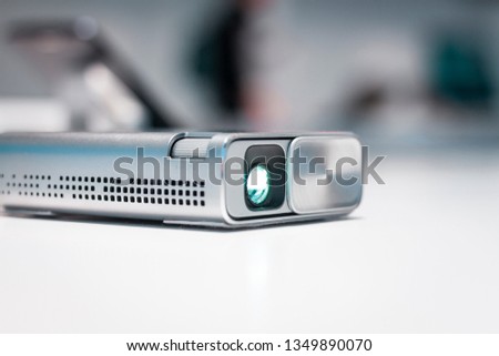 Security and CCTV mini device for any kind of surveillance. Small silver body, high resolution camera sensor, and lens. Futuristic design, spy game. Privacy and personal data issues, pocket projector.