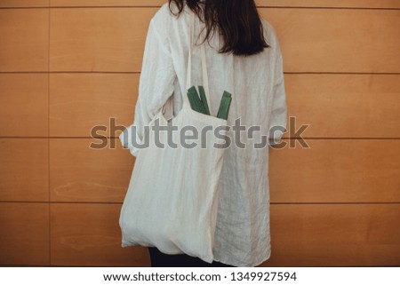 Cropped picture of a young hipster girl with a blank cotton tote bag with fresh eco farm vegetables inside from the local grocery store and  a leek. Concept of sustainable shopping