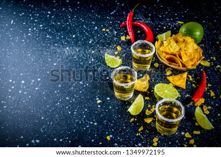 Cinco de Mayo celebration concept. 5th May Mexican party's drinks - margarita cocktail, tequila shots with lime, hot chili peppers and chips, dark background copy space 