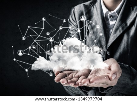 Businessman in suit keeping cloud with network connections in hands with gray wall on background.