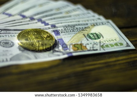 Bitcoin cryptocurrency coin and dollars on a wooden surface