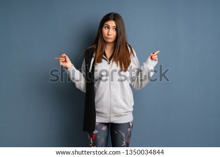 Young sport woman pointing to the laterals having doubts