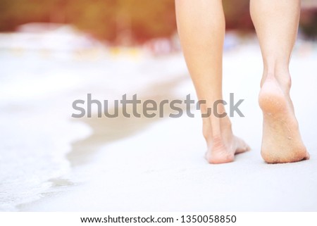 Close up of a lady woman's bare feet walking and footprint at wet on the beach. Vacation on ocean beach, foot on sea sand. Leave empty copy space Enter the text. Shadow from the sun hits the sand.