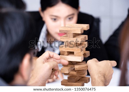 Businessman's hand is trying to hold a tower of wooden blocks game, Alternative risk and strategy in business concept