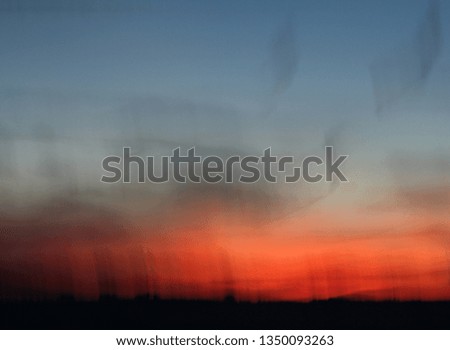 Deliberately out of focus impressionist, abstract image of evening clouds and red sun as night draws in. Beautiful and atmospheric.