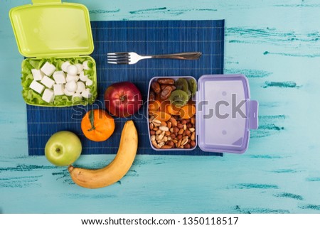 Lunch box with appetizing food and on light wooden table.