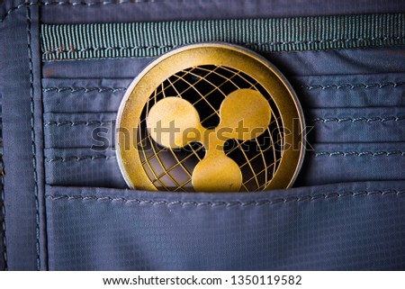 Golden ripple coin. Crypto XRP Coin on dark wood background and wallet. Close-up, macro shot.New Virtual Money 