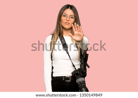Young photographer woman making stop gesture denying a situation that thinks wrong on isolated pink background